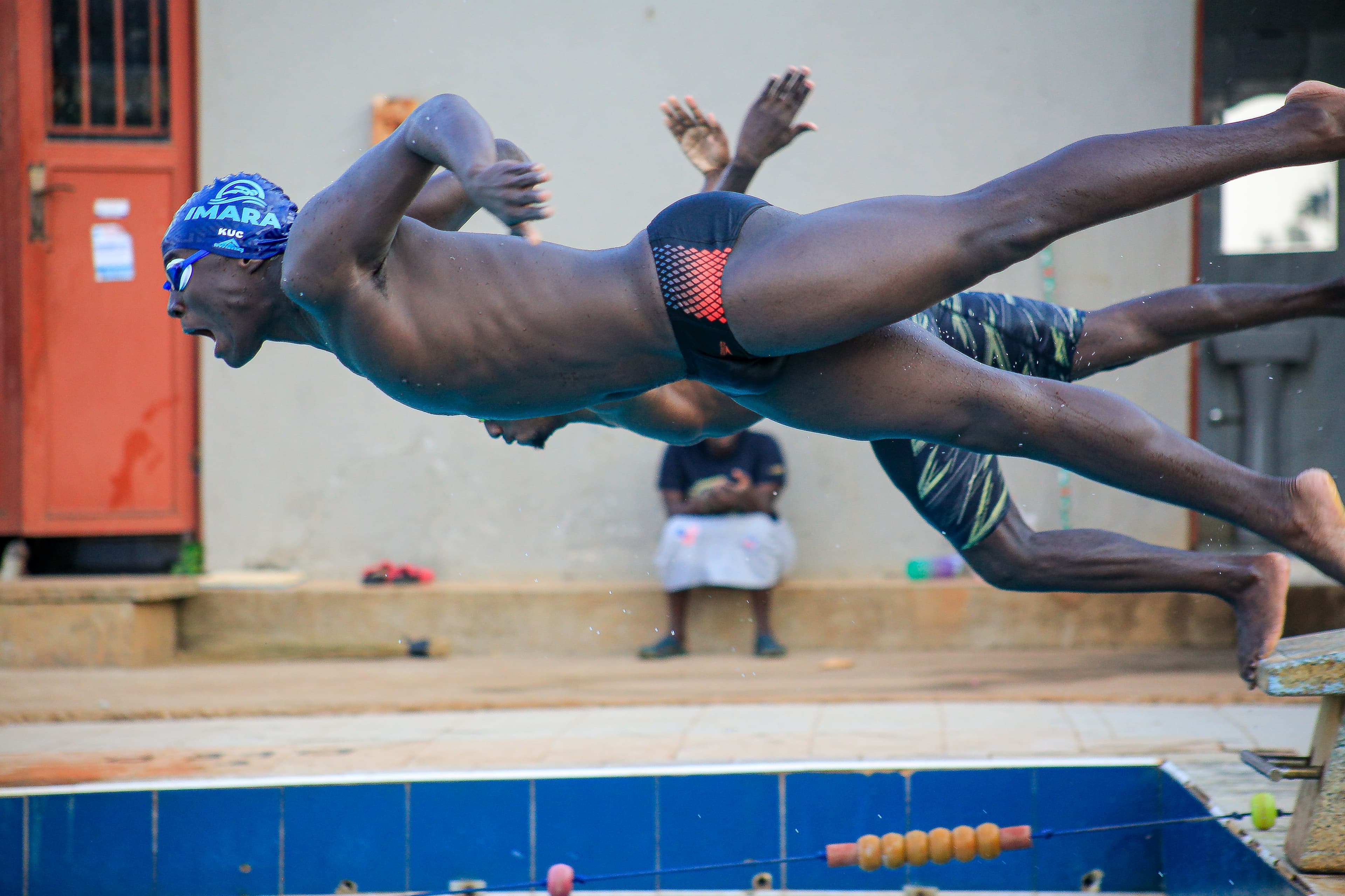 Imara swimmers diving from the poolside at the start of a race